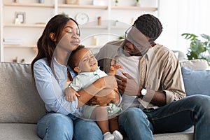 African American parents sitting with crying kid on sofa