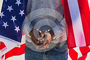 African american person with shackles in his hands and united states flag over his shoulders. Racial repression