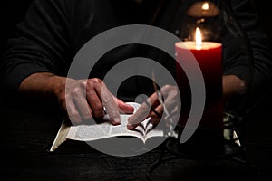 African American Person Studying the Bible Sitting at Desk with Candle photo