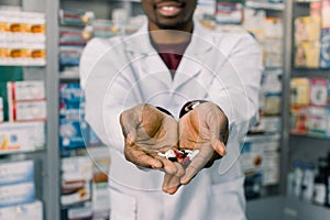 African-american pharmacist man holding tablets pills in the hands. Man`s hands holding a handful of medicine pills, to