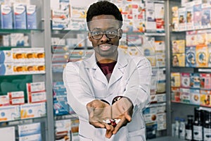 African-american pharmacist man holding tablets pills in the hands. Man`s hands holding a handful of medicine pills, to