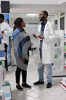 African american pharmacist recommending woman vitamin c in drugstore