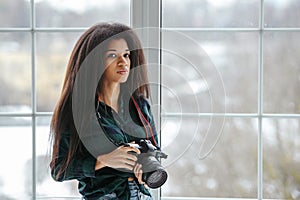 An African-American photographer girl with a camera. Photo shoot in the studio