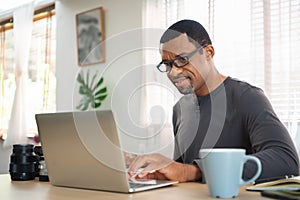 African American photographer man working on laptop