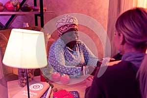 African american plump fortune-teller in ethnic headwear holding witchery accessory