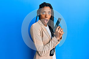 African american police woman holding gun afraid and shocked with surprise and amazed expression, fear and excited face