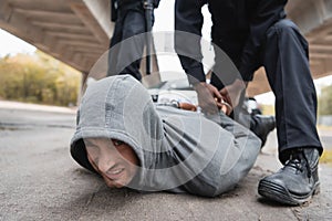 African american policeman handcuffing offender lying