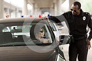 african american policeman talking to young woman sitting