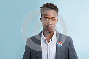 African american politician in suit with pinned vote button on blue