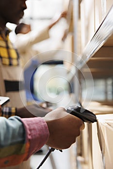 African american postal worker hand scanning parcel in warehouse