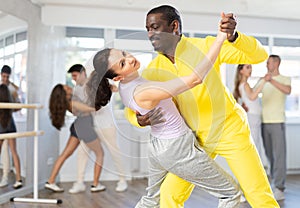 African American practicing bachata with brunette in dance class