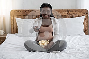 African American Pregnant Lady Relaxing At Home, Watching Tv And Eating Popcorn