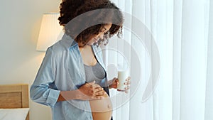 African American Pregnant woman holding a glass of milk