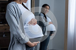 african american pregnant woman looking at her belly