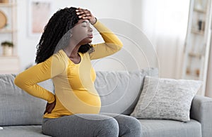 African american pregnant woman suffering from headache at home