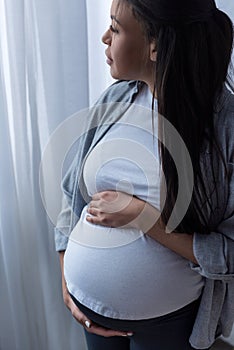 african american pregnant woman touching her belly while looking