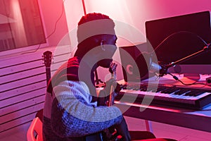 African american professional musician recording bass guitar in digital studio at home, music production technology