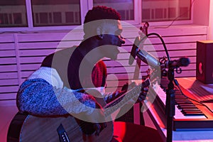 African american professional musician recording guitar in digital studio at home, music production technology concept.