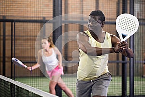 African American ready to hit two handed backhand during padel match