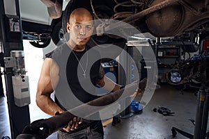 African American repairman removing drive shaft