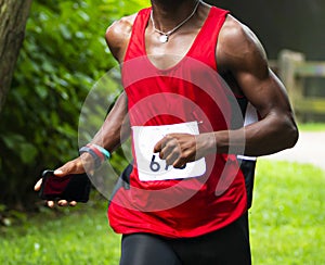 African American runner running a 10K trail race in the woods