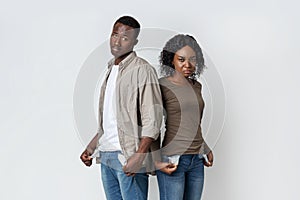 African american sad couple demonstrating empty pockets