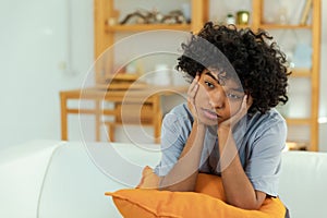 African american sad thoughtful pensive unmotivated girl sitting on sofa at home indoor. Young african woman ponder look