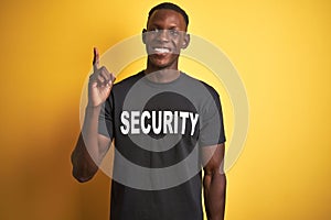 African american safeguard man wearing security uniform over isolated yellow background pointing finger up with successful idea