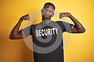 African american safeguard man wearing security uniform over isolated yellow background showing arms muscles smiling proud