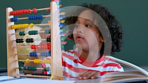African American schoolboy learning mathematics with abacus at desk in a classroom
