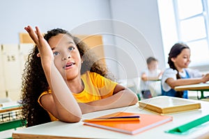 african american schoolgirl raising hand to answer teachers question