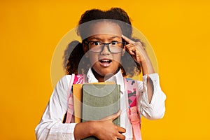 African American Schoolgirl Twisting Finger At Temple, Yellow Background