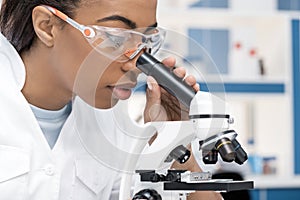 African american scientist in lab coat working with microscope in chemical lab