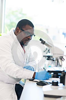 African-american scientist working in lab. Doctor making microbiology research. Laboratory tools: microscope, test tubes