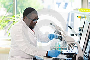 African-american scientist working in lab. Doctor making microbiology research. Laboratory tools: microscope, test tubes