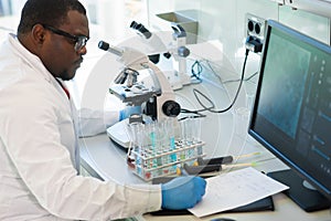 African-american scientist working in lab. Doctor making microbiology research. Laboratory tools: microscope, test tubes