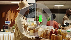 African american seller holding smartphone app with greenscreen