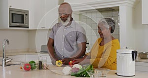 African american senior couple chopping vegetables together in the kitchen at home