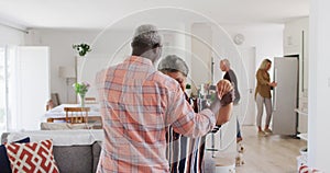 African american senior couple dancing in a living room with senior caucasian couple in background