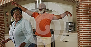 African american senior couple dancing together in the kitchen at home