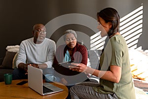 African american senior couple having meeting with asian female financial advisor at home