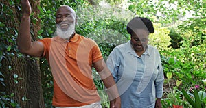 African american senior couple holding hands smiling while walking together in the garden