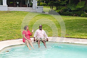 African american senior couple spending leisure time together at swimming pool on sunny day