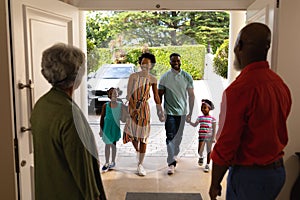 African american senior couple welcoming their family while standing on the front door at home