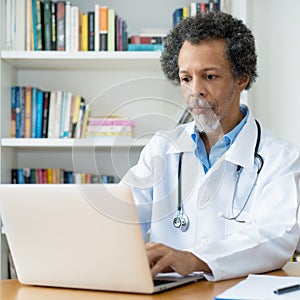 African american senior doctor working at computer