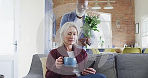 African american senior man giving a flower bouquet to his wife at home