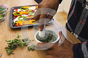 African american senior man preparing healthy meal with vegetables and seasonings in kitchen