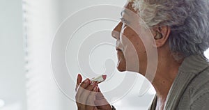 African american senior woman applying lipstick while looking in the mirror at home