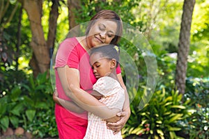 African american senior woman and granddaughter embracing each other with eyes closed in backyard