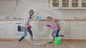 African american sisters mopping kitchen floor